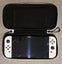 White Nintendo Switch OLED with screen protector, case, and handheld controller Carousel 4