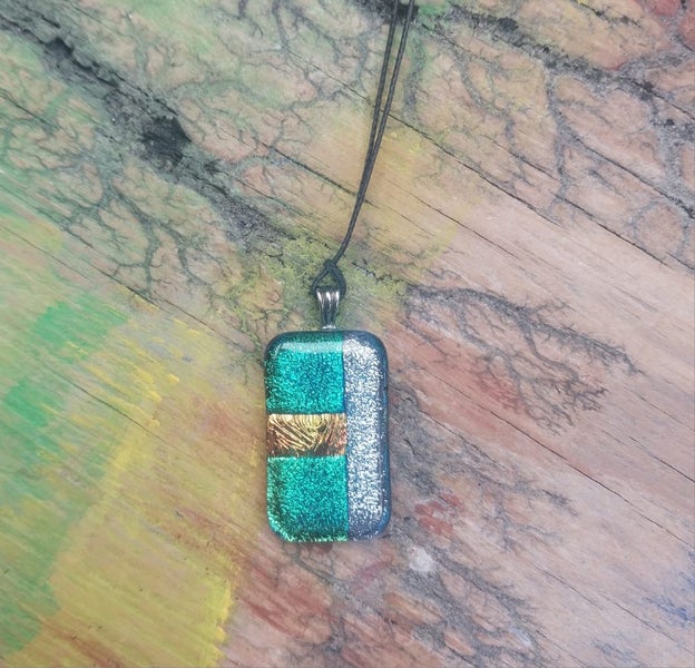 Green & silver metallic foil art glass pendant on new waxed cord. Carousel 1