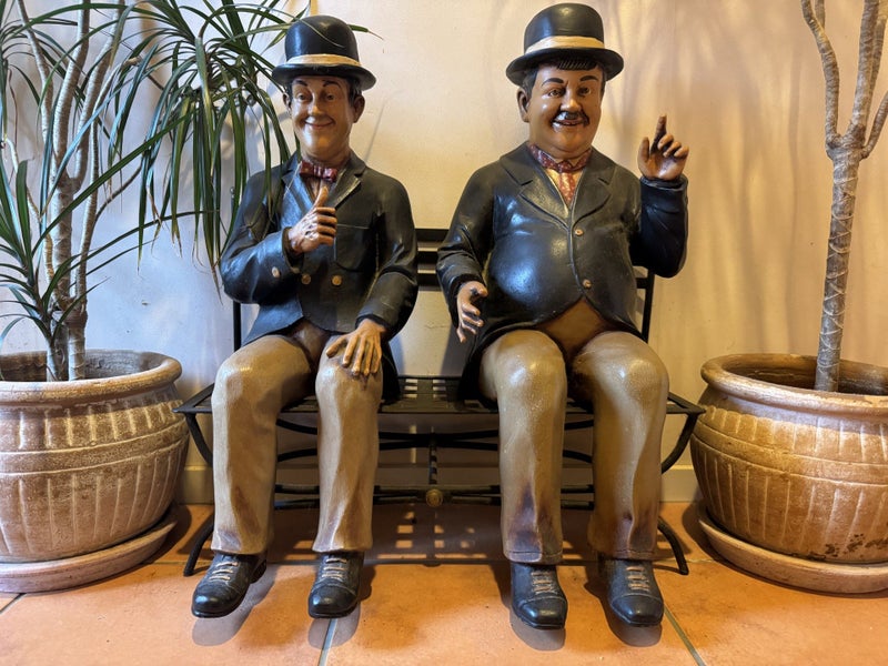 Laurel and Hardy sitting on a bench - with two potted plants64481660274305111