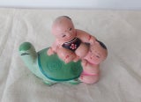 A Clay Sculpture Asian Good Luck Babies sitting on a turtle