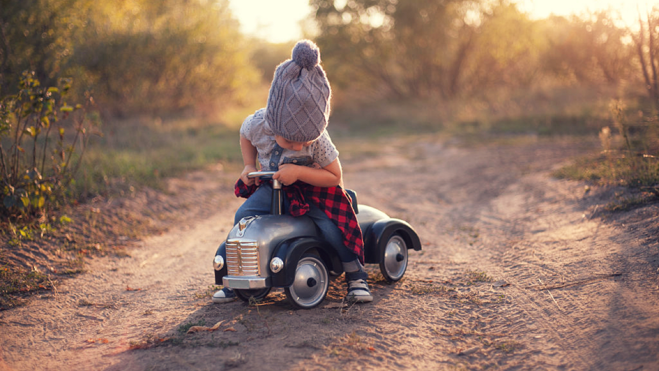Toddler playing on a toy truck.