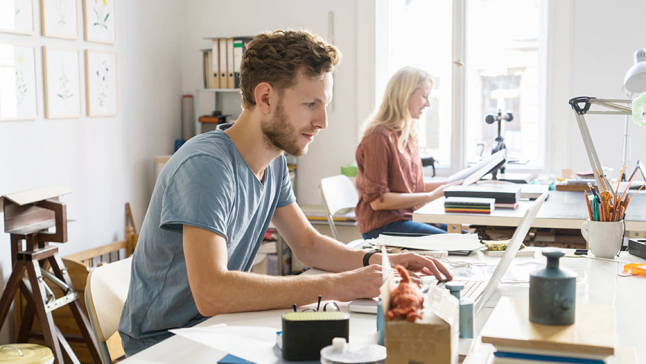 Man working on laptop in sunny office.