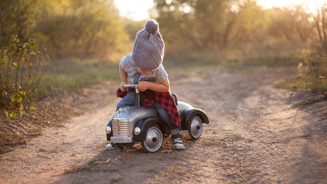 Toddler playing on a toy truck.