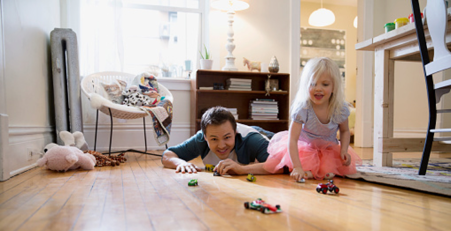 Father and daughter playing together with toy cars.